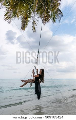 A Young Girl Riding On A Swing. Swing Suspended On The Palpe Above The Water