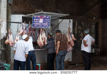 Kashgar, Xinjiang, China - August 14, 2012: Uyghur Man In A Butcher Shop At Street Market In The Cit