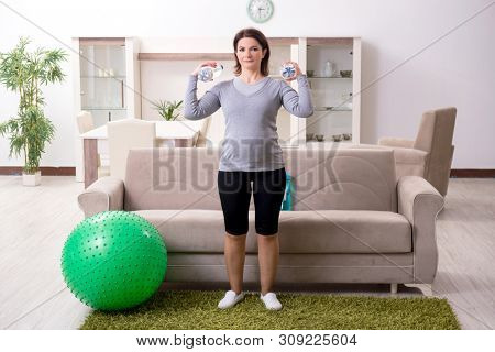 Aged pregnant woman doing exercises at home 
