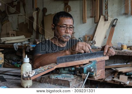 Gianyar,bali/indonesia-may 30 2019: A Guitar Craftsman Is Measuring And Make Sure It Is A Precision