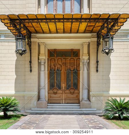 Cairo, Egypt- June 29 2019: Decorated Antique Wooden Door In A Stone Bricks Wall, Sunshade And Two L