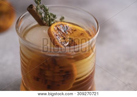 Whiskey Sour Cocktail With Tangerine Slices And Ice Cubes Decorated With Cinnamon And Thyme. Alcohol