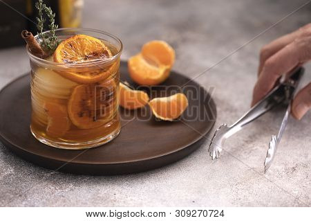 Whiskey sour cocktail with tangerine slices and ice cubes decorated with cinnamon and thyme. Alcohol
