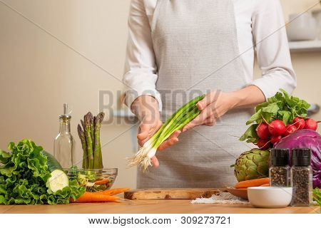 Chef Cook With Green Onions, On A Light Background. The Concept Of Losing Healthy And Wholesome Food
