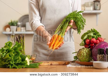 Chef Is Holding A Fresh Carrot. The Concept Of Losing Healthy And Wholesome Food, Detox, Vegan Eatin