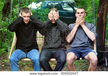 Brusilov, Ukraine - July 13, 2017: Three Guys In The Forest Are Sitting On A Swing. Funny Guys. Abst