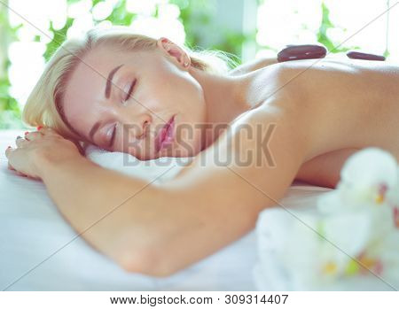 Young woman in spa salon, getting stones massage.