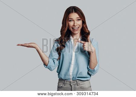 Look Over Here! Attractive Young Woman Looking At Camera And Smiling While Pointing Copy Space Again