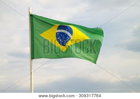 Brazilian Flag On A Blue Sky With Clouds Background