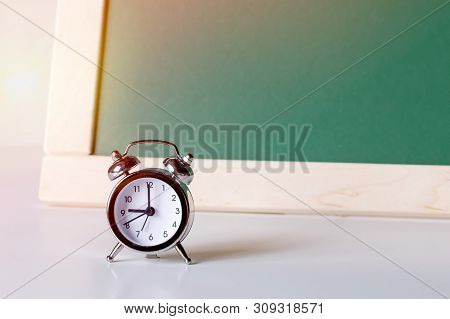 Back To School. Alarm Clock On The Background Of The School Board. School Background With Space For