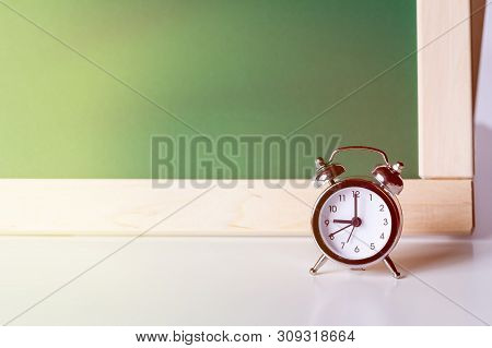 Back To School. Alarm Clock On The Background Of The School Board. School Background With Space For