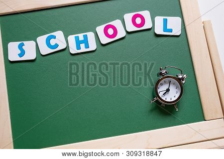 Back To School. Alarm Clock On The Background Of The School Board. School Background With Space For