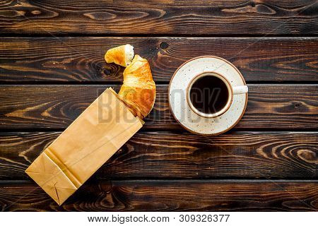 Fresh Pastry With Croissant In Paper Bag And Cup Of Coffee On Wooden Background Top View