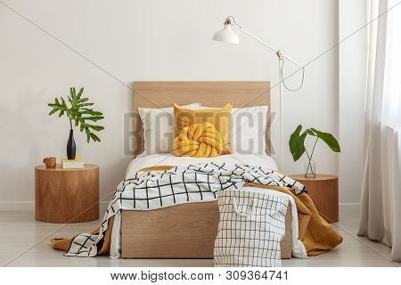 Knot Pillow And Black And White Blanket On Single Bed In Fashionable Interior With Green Leaf In Vas