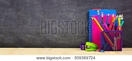 School Supplies On A Wood Desk With Chalkboard Background. Side View. Back To School Concept. Copy S