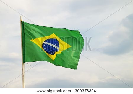 Brazilian Flag On A Blue Sky With Clouds Background