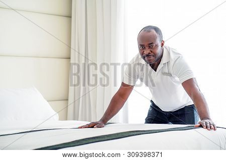 Elderly Maid Making Bed In Hotel Room. Staff Maid Making Bed. African Housekeeper Man Making Bed.