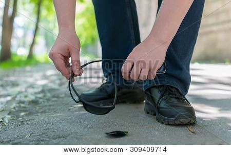 View Of A Man Feet On A City Street That Stands On An Asphalt Pedestrian Road And Raises Fallen And 
