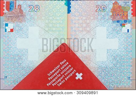 Close Up View Of One Swiss Passport Laid Over Another Open Passport In The Background