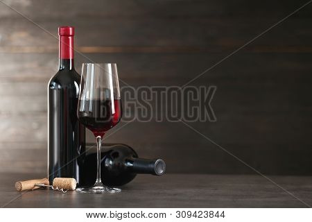 Composition With Glass And Bottles Of Red Wine On Table. Space For Text