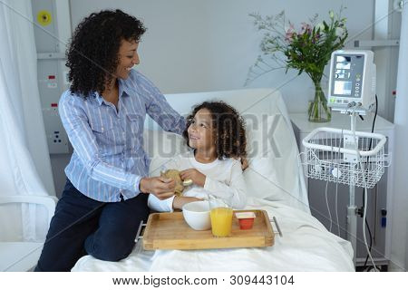 Side view of happy mixed race mother and son looking at each other in the ward at hospital