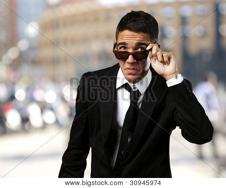 retrato de um homem de negócios, tirar os óculos de sol em uma cidade lotada
