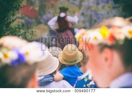 Spectators In National Costumes With Wreaths Of Flowers On Their Heads Watch A Concert With Dances A