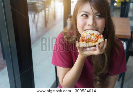Happy Asian Girl Eating Tasty Pizza At Restaurant, Close Up.
Young Woman Holding And Bite Sliced Pie