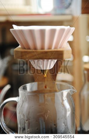 Brewing Coffee In Pink Ceramic Origami Dripper On Wooden Stand. Alternative Manual Brew. Close Up