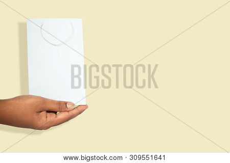 Concept Of Give Paper Bag, Hands Holding Colorfull Empty Blue Color Paper Shopping Bag On Yellow Bac