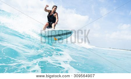 HIMMAFUSHI / MALDIVES - MARCH 08, 2019: Hispanic surfer rides the ocean wave on the Sultans surf spot in Maldives