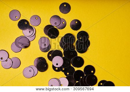 Embroidery Products And Tools. Black Sequins On Yellow Background.