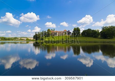 Castle On The Lake. Beautiful Scene With Ancient Svirzh ( Svirz ) Castle On The Hill Against The Blu