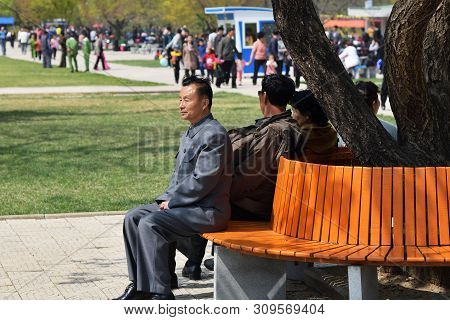 Pyongyang, North Korea - May 1, 2019: Senior Man Resting On The Bench In The Taesongsan Funfair. Is 