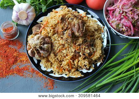 Pilaf On A Platter Of Meat And Spices.pilaf In A Plate On A Wooden Background, Top View.  The Concep