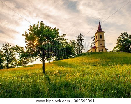 Small Church In The Middle Of Lush Green Spring Landscape On Sunny Day. St. Peter And Pauls Church A