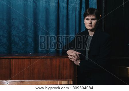 Classical Musician Performer Near Piano. Musical Artist In Dark Room Of Culture House. Portrait Of C