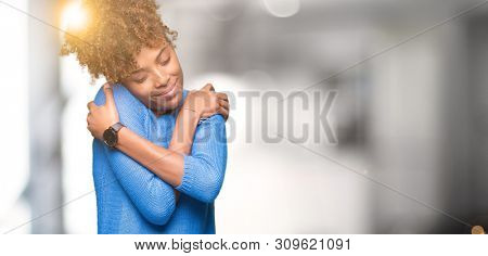 Beautiful young african american woman over isolated background Hugging oneself happy and positive, smiling confident. Self love and self care