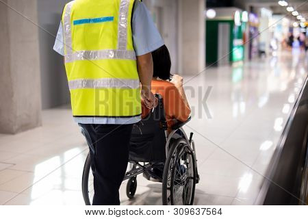 Caretaker Push Elderly Woman On Wheelchair In Airport Terminal.