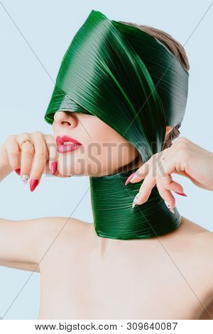 A close up portrait of a beautiful girl with a head rolled up in a leave posing in the studio over the white background. Beauty, nature, make up.