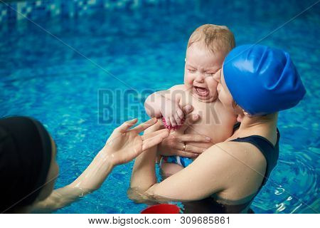 Little Blond Baby Boy In Diaper Crying, Afraid Of Water And Swimming. Mother Calming Baby, Holding O