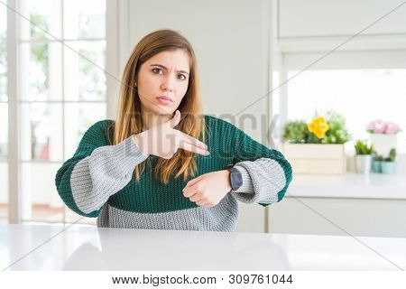 Young beautiful plus size woman wearing casual striped sweater In hurry pointing to watch time, impatience, upset and angry for deadline delay