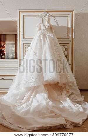 Elegance Fashion Wedding Dress Hanging In Bedroom. Traditional Long Fabric Silk Bridal Clothing For 