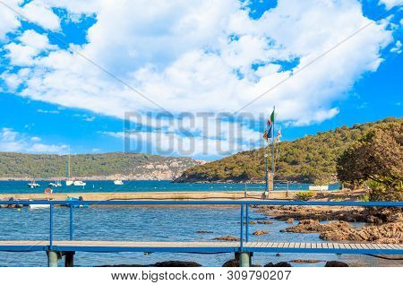 View Of Gulf, Pier And Beach Of Tramariglio In A Sunny And Cloudy Day, In The Capocaccia Coast