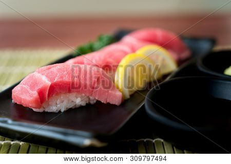 Otoro Tuna Sushi On Black Plate Along With Japanese Sauce And Green Leaf Decoration, Japanese Food, 