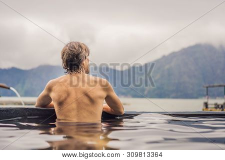 Geothermal Spa. Man Relaxing In Hot Spring Pool. Young Man Enjoying Bathing Relaxed In A Blue Water 