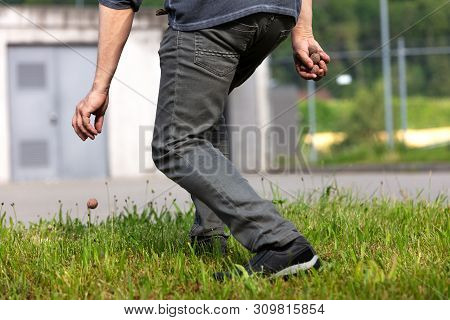 Man Is Holding And Throwing Seed Balls Or Seed Bombs In Front Of A Ugly Grey Building, Concept Gueri