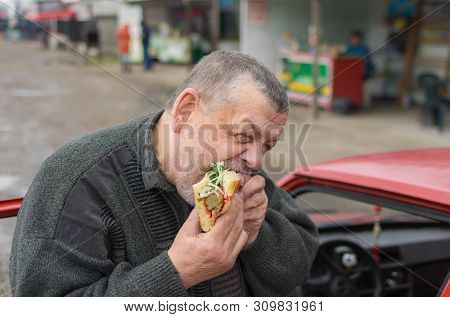 Hungry Caucasian Senior Driver Eating Lyulya Kebab In Lavash Outside Of His Car