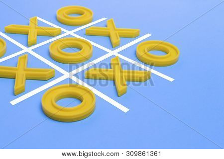 Yellow Plastic Crosses And A Toe And A Ruled Field For Playing Tic-tac-toe On A Blue Background. Con