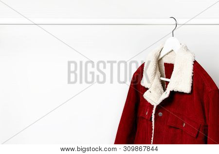 Red Corduroy Men's Jacket On White Coat Hanger On Rod Against Light Wall Flat Lay Copy Space. Male F